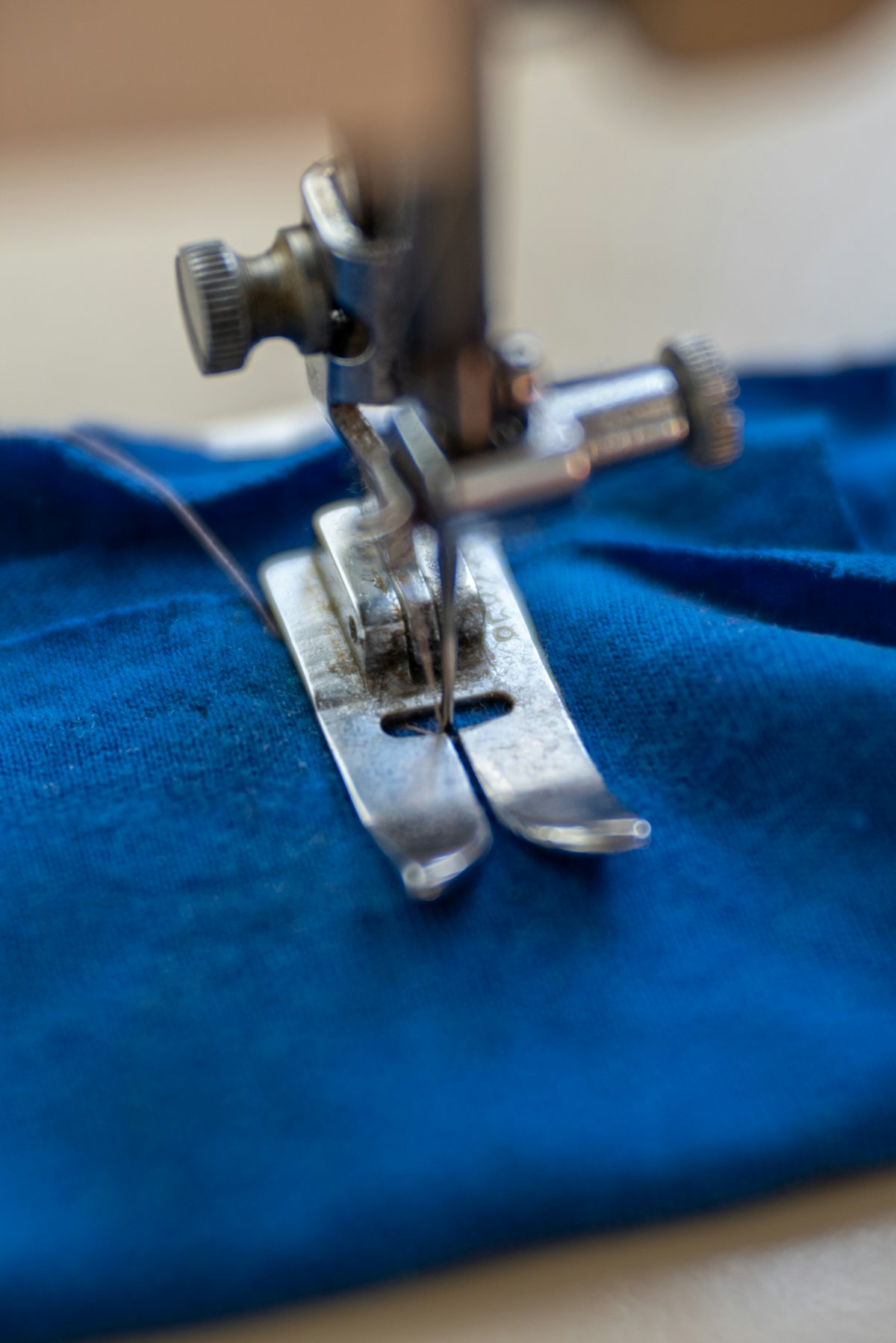 Máquina de coser trabajando sobre una tela azul