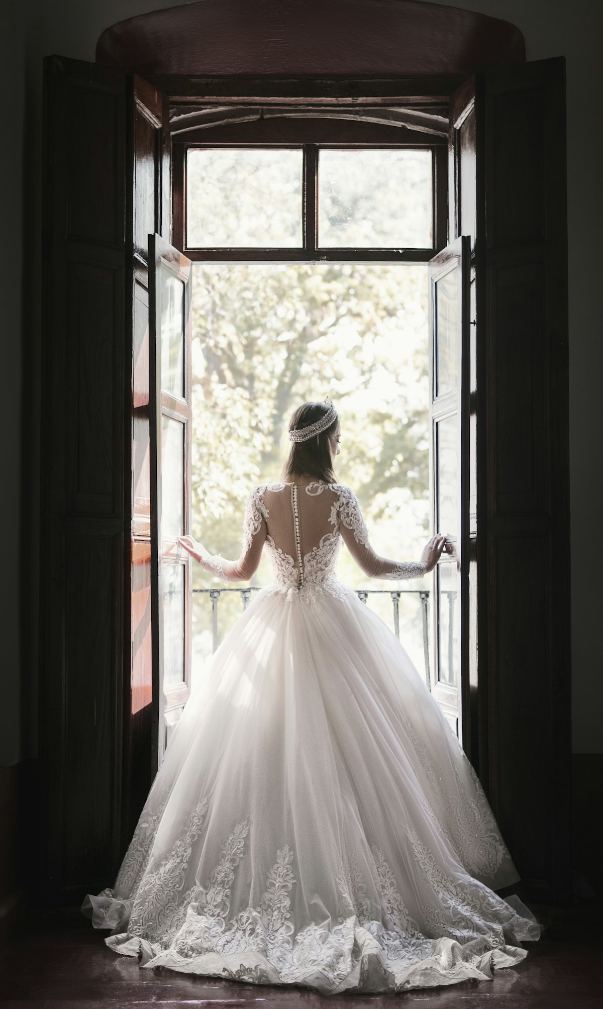 Novia junto a una ventana con el vestido de encaje ya ajustado